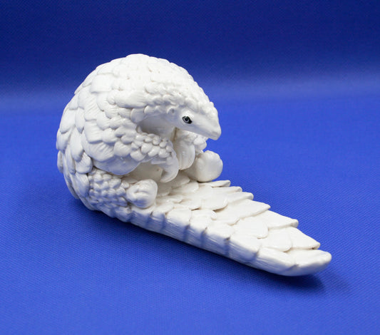 Small white pangolin sitting tail out 2