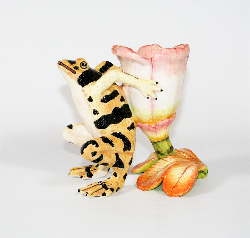 Yellow frog with black speckled spots and pink and white flower candle holder