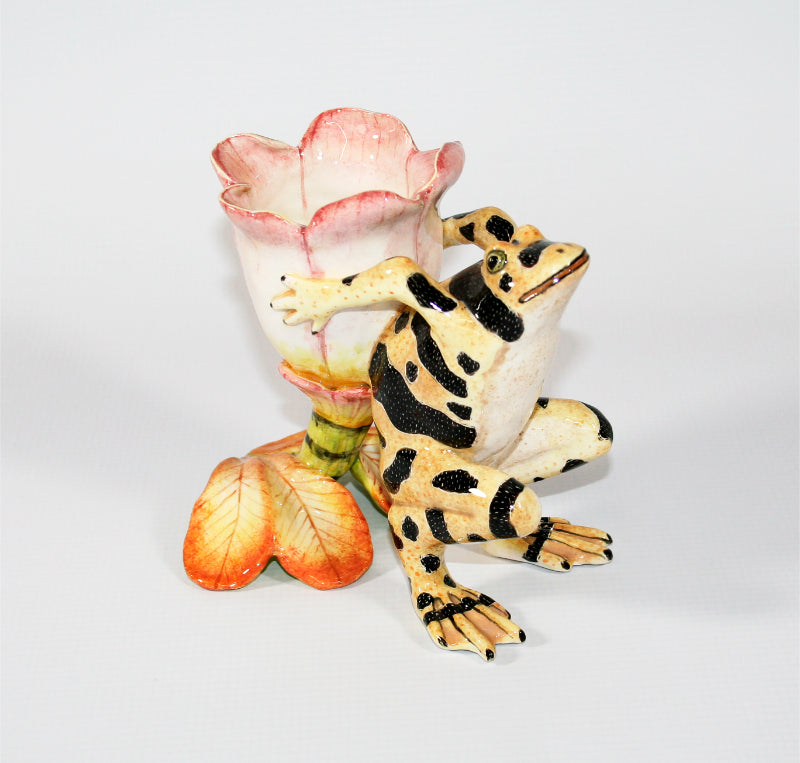 Yellow frog with black speckled spots and pink and white flower candle holder