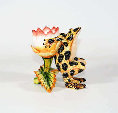 Orange yellow frog with black speckled spots and pink white and yellow flower